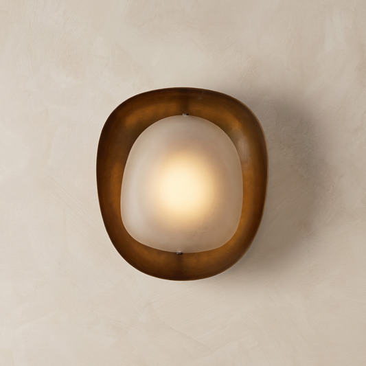AX924 sculptural bronze wall sconce lit – hand-finished bronze ring with glowing frosted glass diffuser on plaster wall