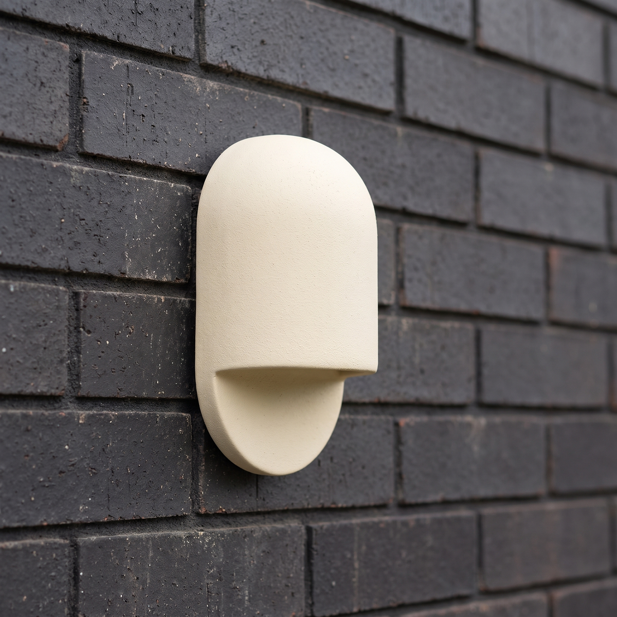 AX472 outdoor ceramic wall sconce in white, arched pill shape mounted on a dark brick exterior wall